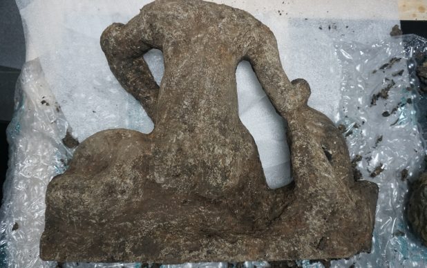PROJECT - Stabilisation, cleaning and conservation assessment of Roman stone sculpture comprising 1no. main body and 1no. head (SF123, C1304; Project Code: EX FLT 23) Size – Head 135mm x 210mm x 150mm Body 700mm x 200mm x 540mm Initial observations – The sculpture was fully encased in damp burnt pyre remains. This was beginning to crack as it dried. Treatment– The sculpture was carefully cleaned with deionised water and soft brushes, some of the harder burnt pyre remains were removed using dental tools keeping clear of the substrate. When some of the pyre remains where removed and examined they had a slight dusting of stone, a fragment was also found in the spoils (RS01). Once all remains were removed the sculpture was poulticed in acid free tissue paper and allowed to dry. When checked there was no sign of efflorescence on the substrate. The sculpture was observed over 4 days, with no salts visible. We did find three areas that required consolidation. These were treated with a 3% solution of Paraloid B72 in acetone (W/V). The lower RHS had slight cracking, possibly caused by the heat of the embers, plus 2 of the fingers were friable and required consolidation. Fig no.1 Showing in red areas treated with Paraloid B72. Findings – We found no sign of poly-chrome. The front of the sculpture has banding of an orange colour which we feel may be the results of the stone being burnt on the still hot embers. This is not as apparent on the back. We feel the breaking of the head from the body had been carried out about the same time that the sculpture was buried. The break on the head had fractures which tapered to a fragile feather edge. This tapering would be broken off with ease with frequent handling. The fragment was used for microscopic identification of the stone. 20x Magnification of RS01. The shape of the granuals and the colour and texture of the sample would indicate that the sculpture is made from Kentish Rag or possibly Hassock stone.